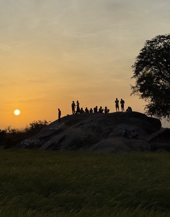People watching the sunset from the top of a rock
