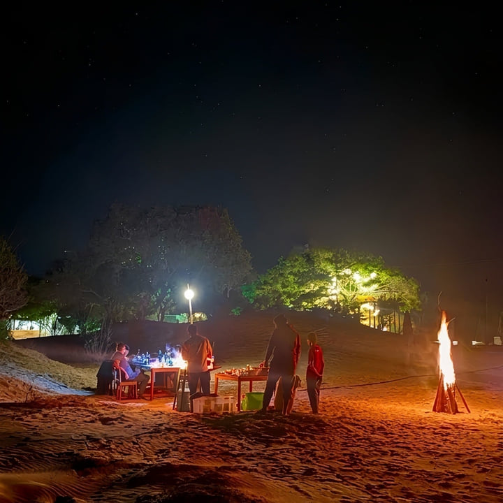 A fire and a table set on the sand at Arugam Bay after dark