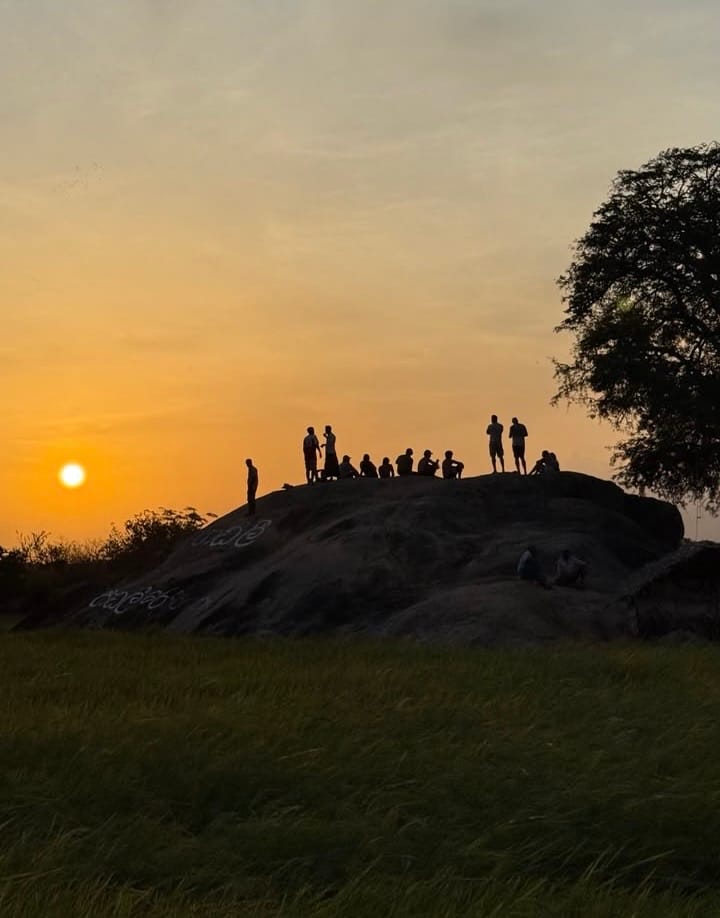 People watching the sunset from the top of a rock