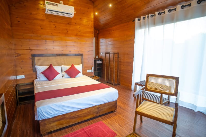 A timber villa bedroom at Arugam Bay with a cane chair by the curtained glass door