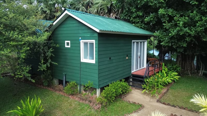 The green timber cabin at Leopard Inn Wilpattu, with the river behind it