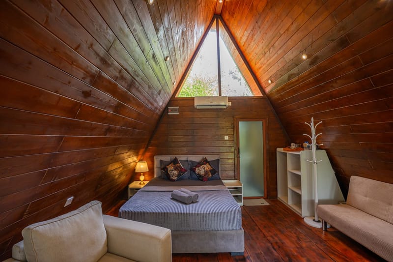 Inside the A-frame villa: the bed beneath the tall triangular window