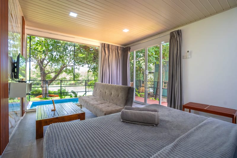 A Wilpattu villa bedroom with the plunge pool and the river through the glass